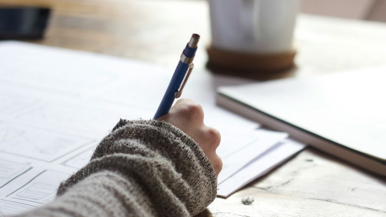 A student planning university applications at a desk with notes and a coffee cup